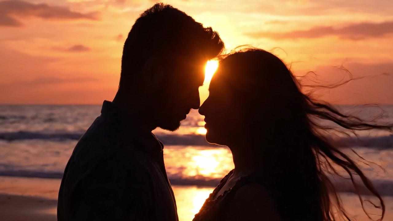 Sagome romantiche contro un tramonto mozzafiato sulla spiaggia, che catturano l'essenza dell'amore e della connessione in un'ambientazione costiera serena.