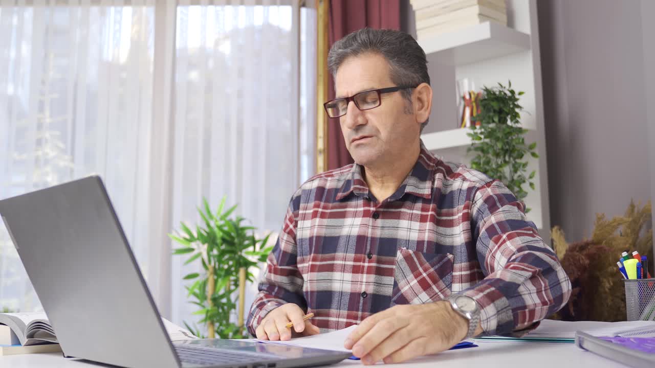hombre de negocios con gafas trabajando en la oficina de casa mirando la computadora portátil.