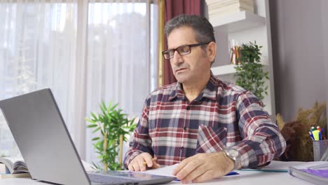 hombre de negocios con gafas trabajando en la oficina de casa mirando la computadora portátil.