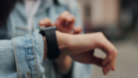 primer plano de la mano femenina escribiendo y tocando el reloj inteligente en su mano afuera en el centro de la ciudad