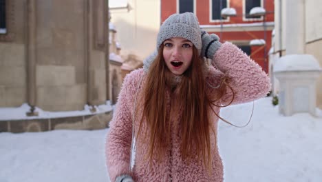 Excited-young-woman-looking-to-camera,-opening-her-mouth-in-amazement,-shouting-wow-on-city-street