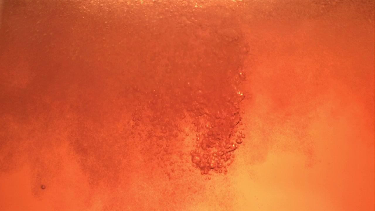 Movimento rallentato di bolle che salgono in un liquido arancione effervescente