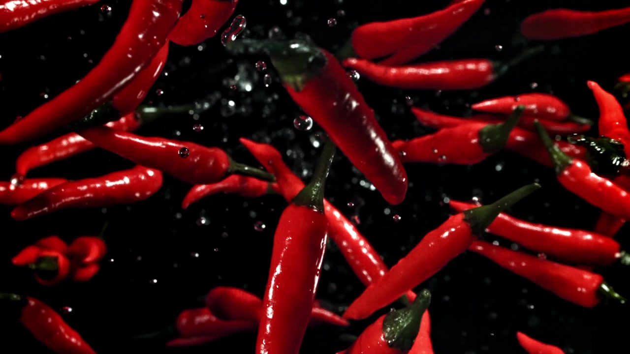 Red Chili Peppers Falling with Water Droplets on Black Background