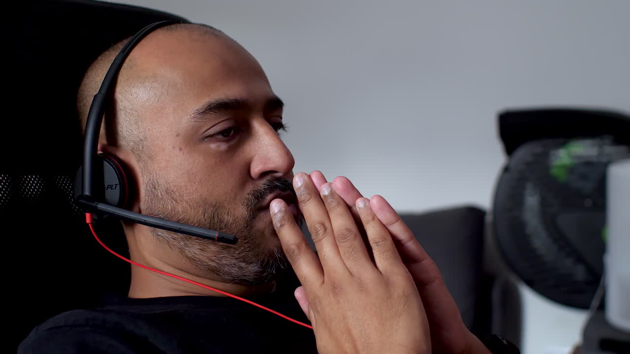 Man with headset in contemplation at office, side view, indoor lighting