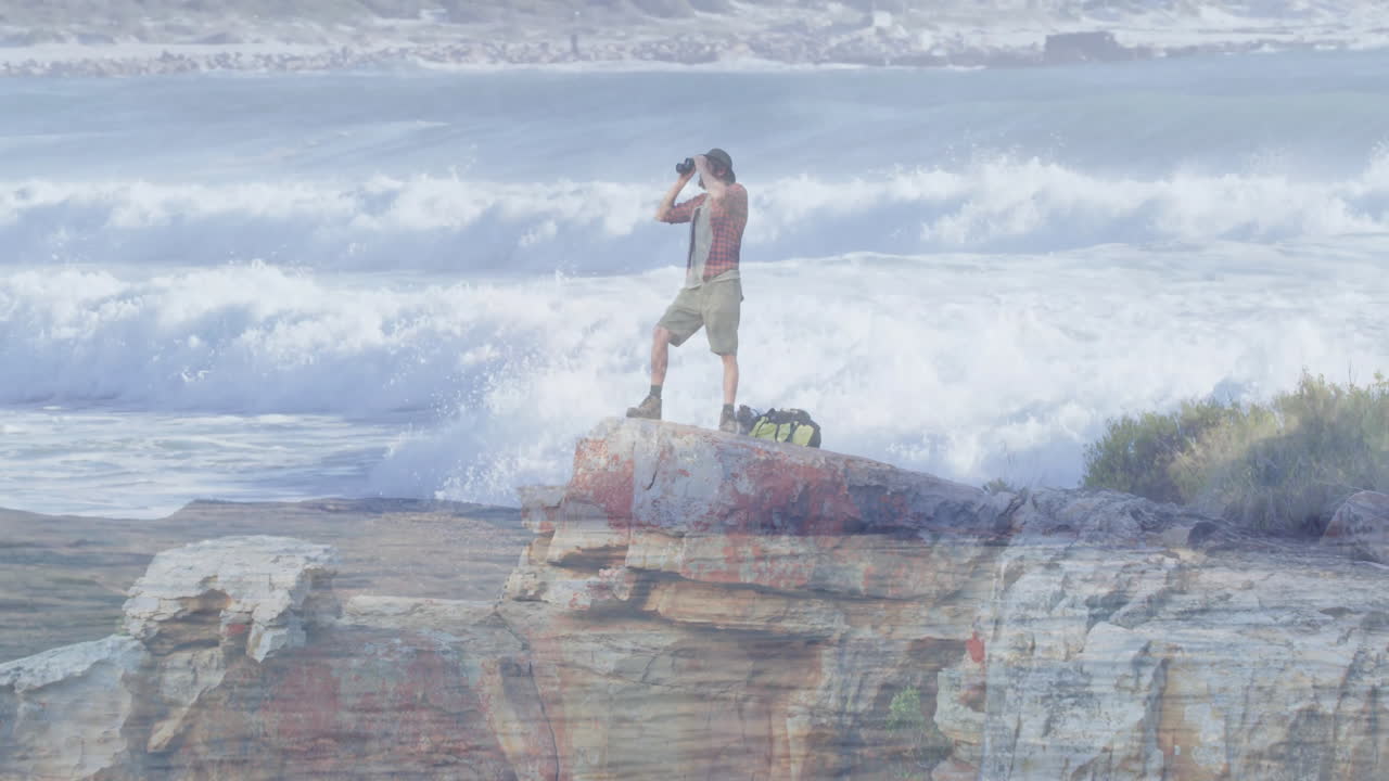 man scanning horizon on rocky coastline, with animated technology charts floating above sea data
