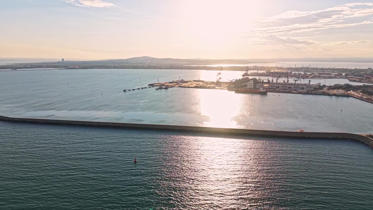 Vista del primo mattino di un porto e della costa con barche e acqua calma che riflette la luce del sole