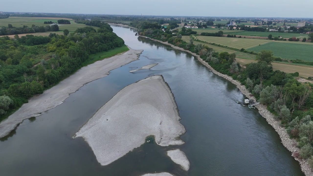 Fiume Po vicino a Isola Serafini, Monticelli d'Ongina, Piacenza, Emilia-Romagna, Italia, che rivela banchi di ghiaia esposti, canali intrecciati a bassa portata e portata ridotta durante l'ondata di calore del 2026, aerea