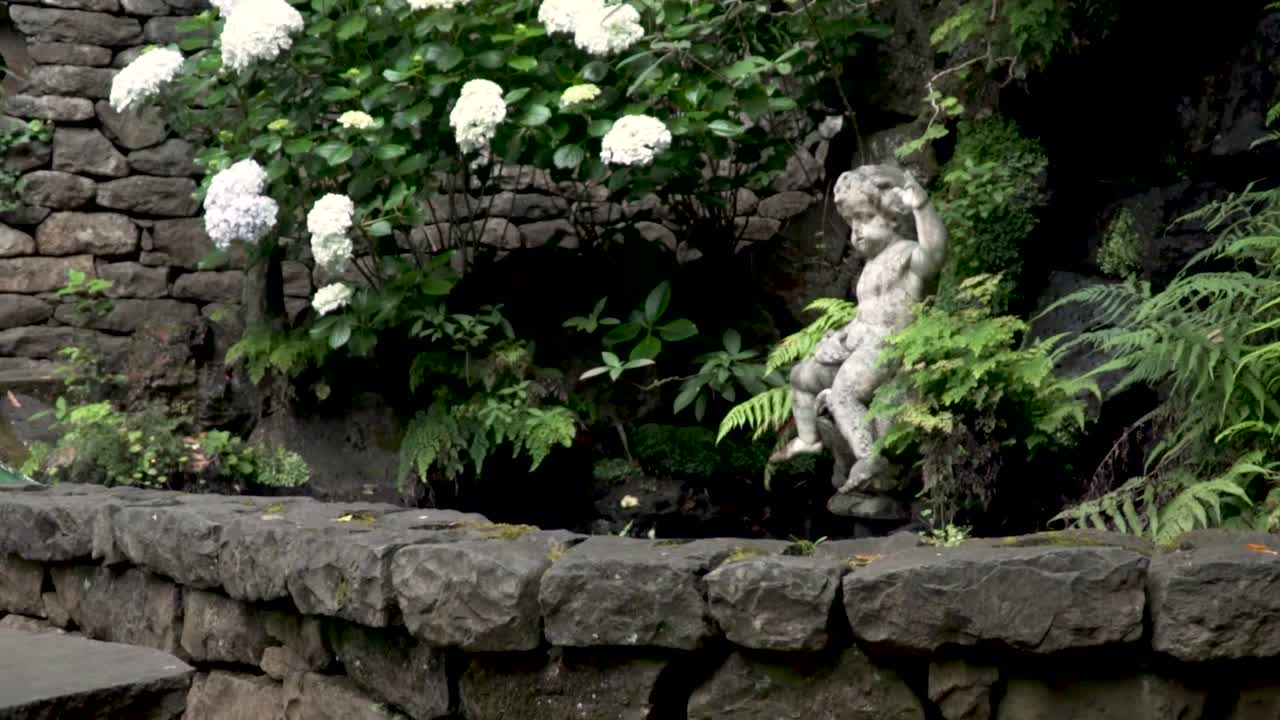 jardín ornamental con esculturas de piedra y hortensias