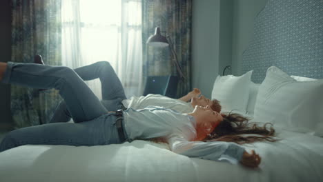 young couple relaxing in modern suite. calm guy girl falling bed hotel room.