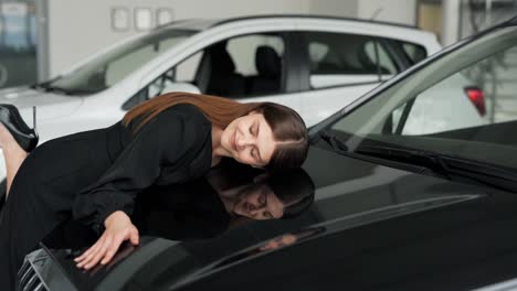 Bella-Joven-Vestida-De-Negro-Abraza-El-Capó-De-Un-Coche-Nuevo