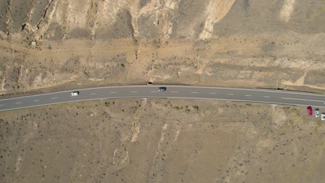 Top-aerial-view-over-the-road-with-traffic-passing,-cars-moving-across-desert-landscape,-location-volcanic-island-landscape,-Lanzarote,-Canary-Island
