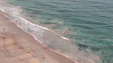 group of people floating in the shallow ocean waters of beach at sunrise
