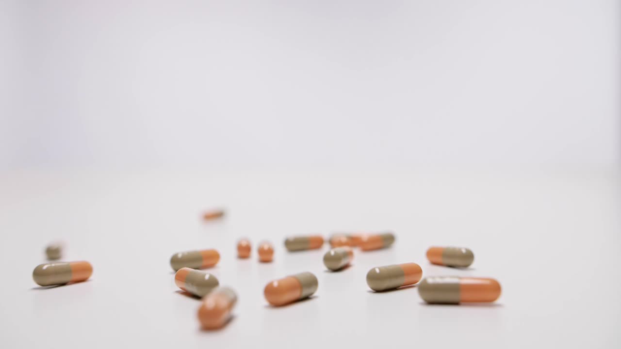 Medicine capsules falling on white background in slow motion.