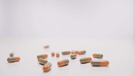 medicine capsules falling on white background in slow motion.