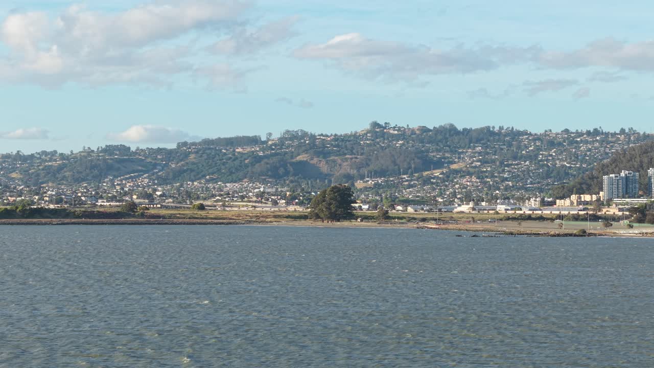 Aerial view taken from the shore of Cesar Chavez Park, reveals winding trails, coastal grasses, and panoramic waterfront scenery.