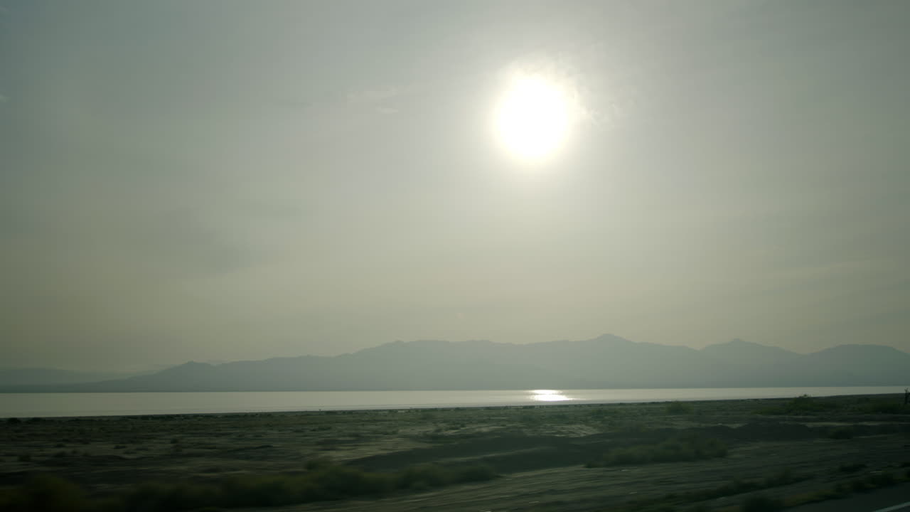 Bright Sun Over Hazy Lake and Distant Mountains