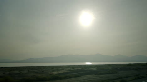 bright sun over hazy lake and distant mountains