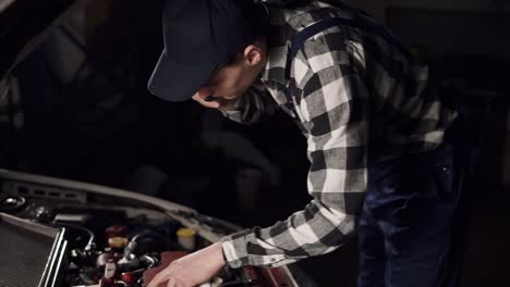 automotive technician calling someone on the phone to consult about the conditions and problems of the car he is repairing