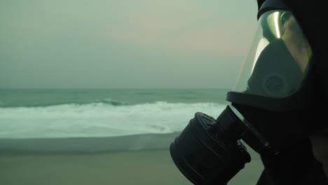 near the ocean a sad man breathes filtered air through a mask