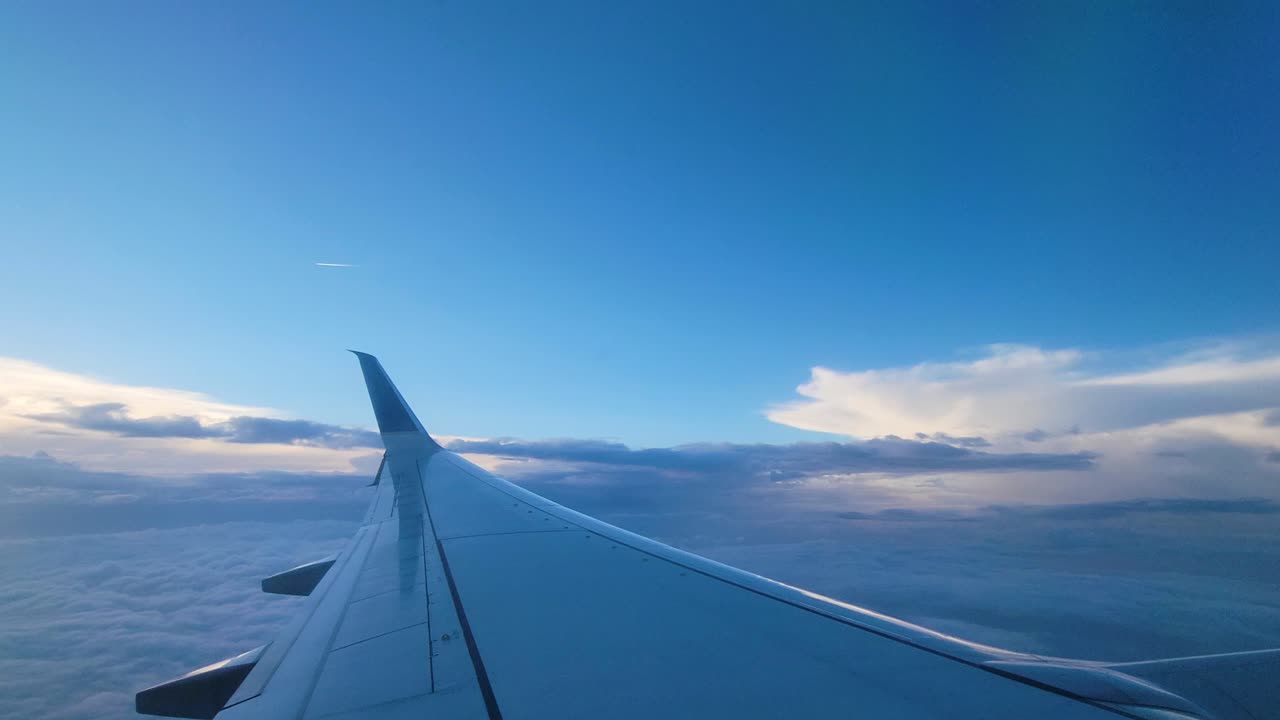 昼間の飛行中、青空と雲を背景にした飛行機の翼