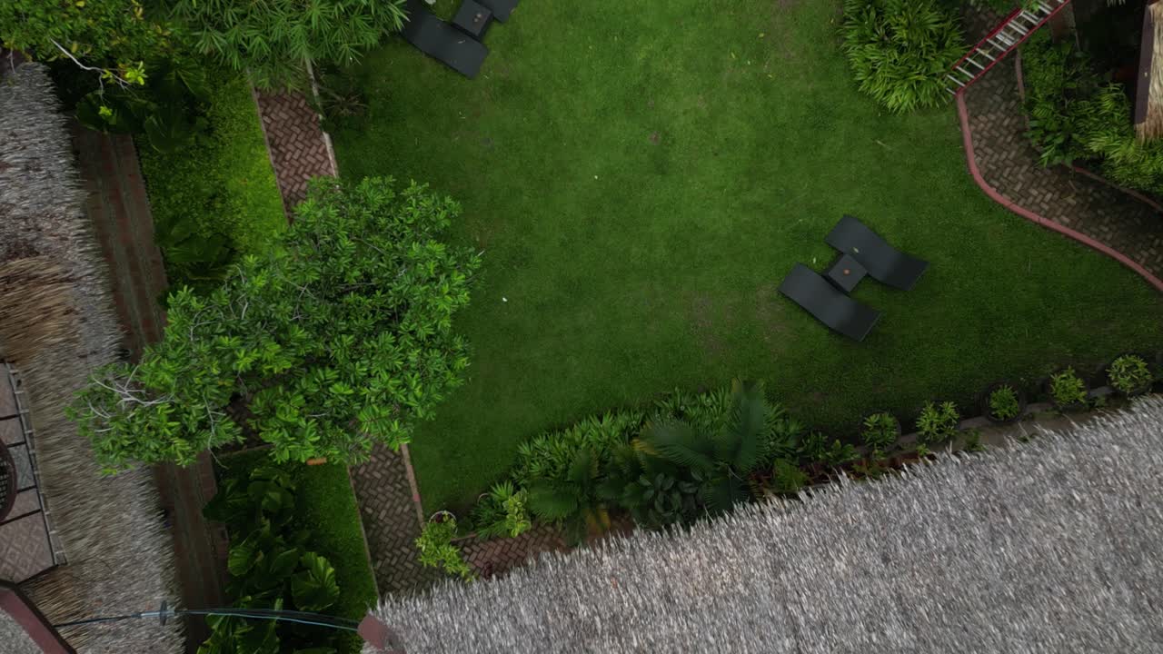 despegue aéreo de un complejo exótico revelando el follaje y el techo del edificio