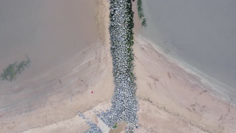 AERIAL:-Top-down-transition-from-grass-covered-sand-dune-to-tidal-sea-defence,-Llanelli,-4K-Drone