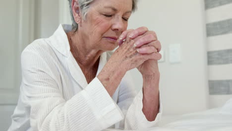 senior woman praying on bed