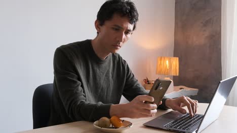 Man-working-on-his-computer-interrupted-by-his-phone