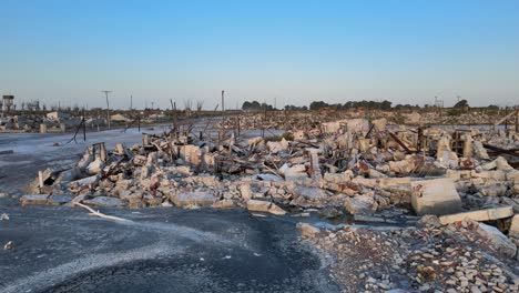 destroyed buildings and piles of fallen rubbles coated with a layer of white salt, town resurfacing from decades of submerged underwater, aerial slow dolly in shot