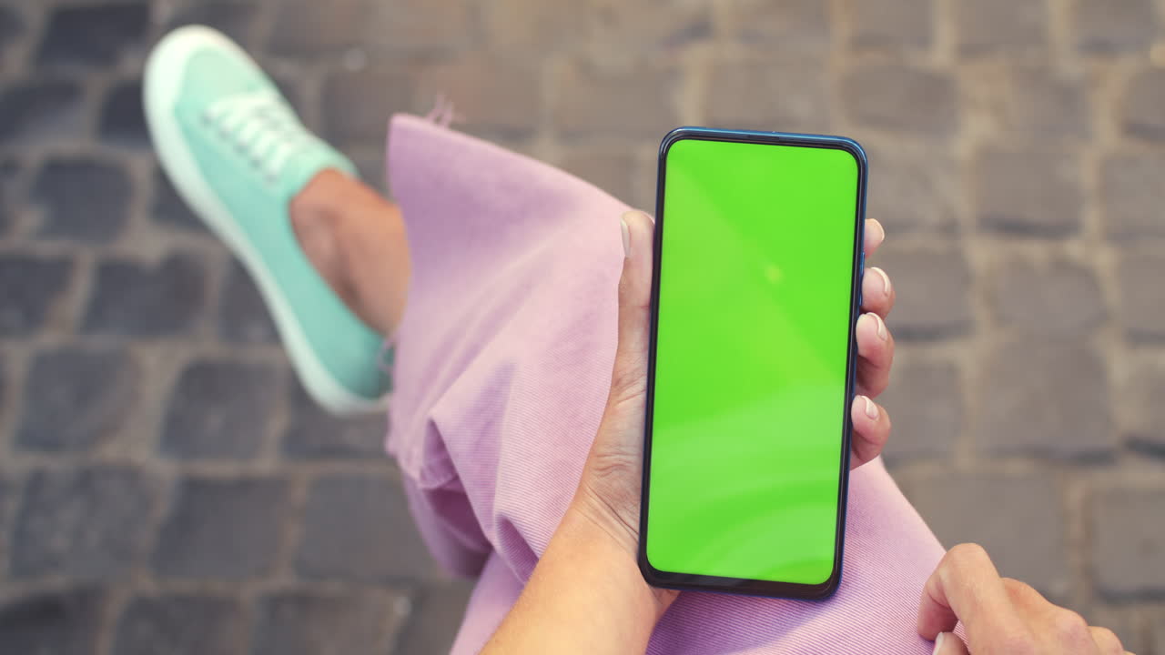 persona que sostiene un teléfono inteligente con pantalla verde al aire libre