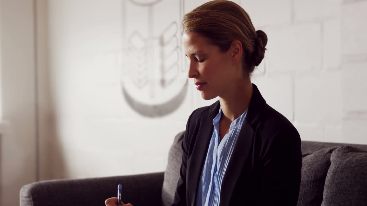 mujer de negocios seria escribiendo notas mientras estaba sentada en el sofá