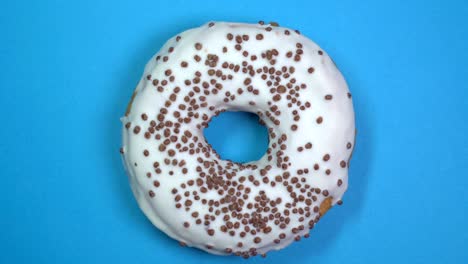 saboroso y fresco rosquilla rosquilla macro disparo de primer plano girando sobre un fondo azul.