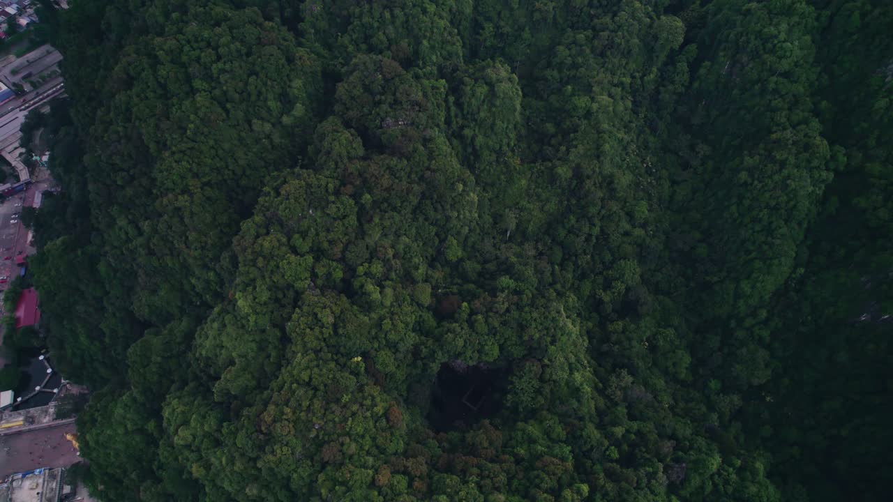 Top-down drone shot of a cave opening in limestone karsts