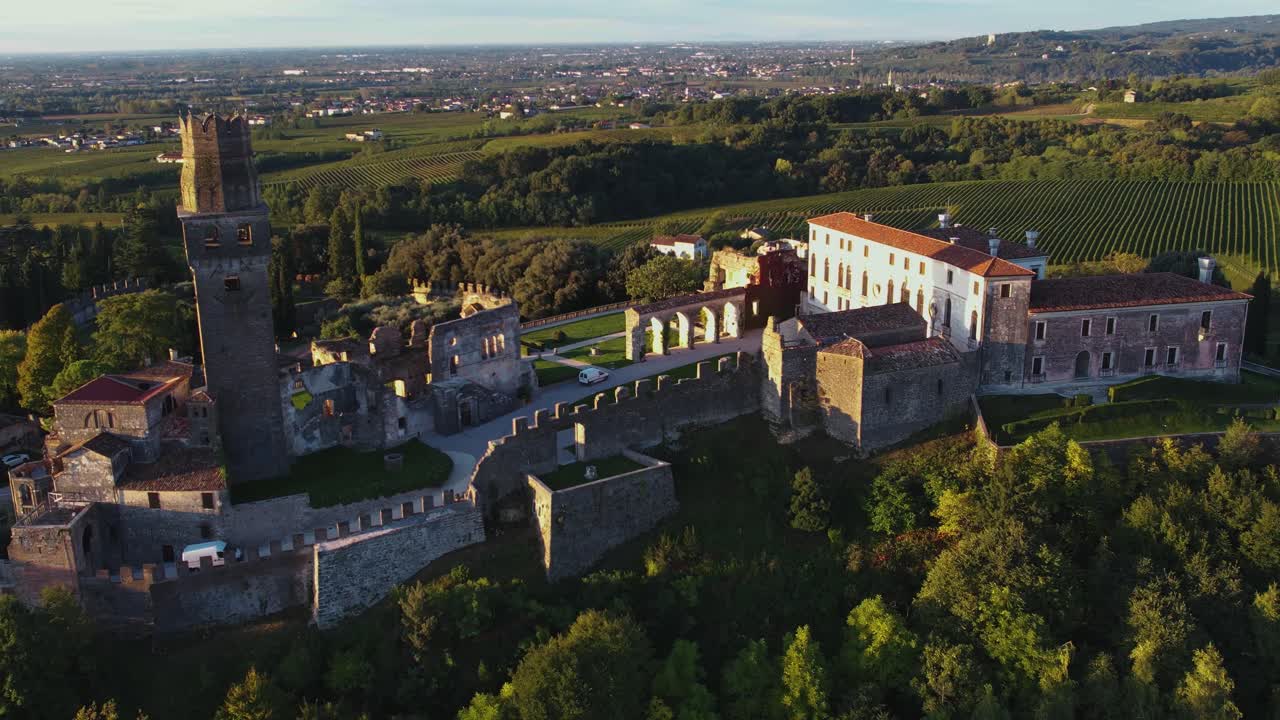 vista panorámica aérea de un castillo medieval en la cima de una colina, rodeado de viñedos de prosecco, en italia