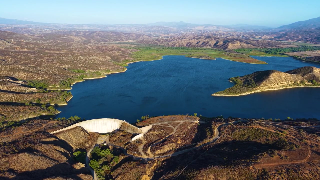 Reservatório de Vail Lake cercado por colinas secas e acidentadas com a Barragem de Vail visível em primeiro plano, fundo de órbita de estabelecimento aéreo