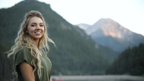 toma en cámara lenta de una hermosa mujer rubia feliz con vistas a una hermosa escena en las montañas