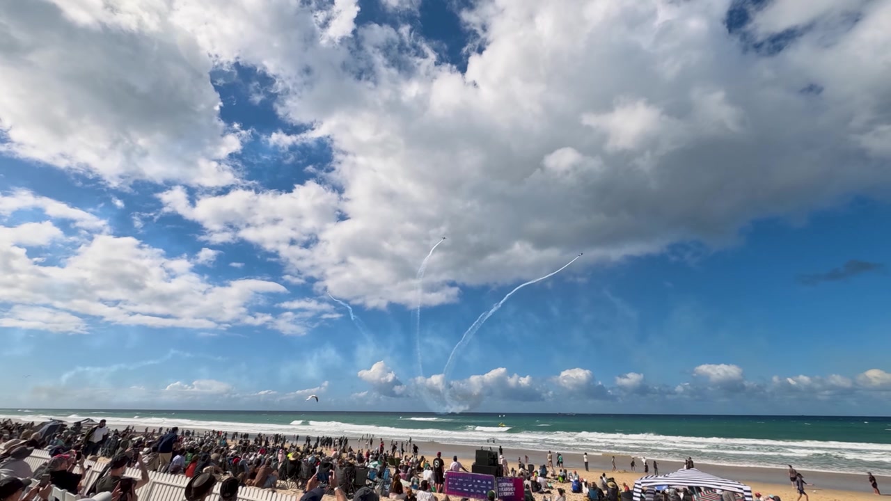 Multitud observando una exhibición aérea sobre la playa