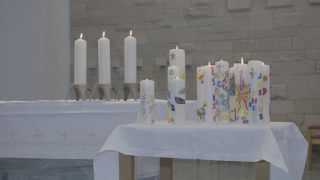 colorful candles stand on an altar, the flames flicker