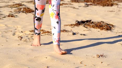young girl in bright legging running along sandy beach