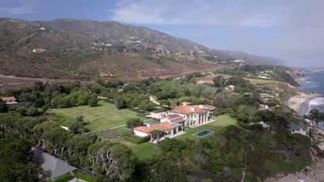 aerial view through clouds, revealing a mansion on the coast of malibu, ca, usa