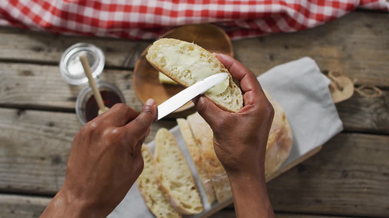Video of slice of bread in hands on wooden worktop seeing from above