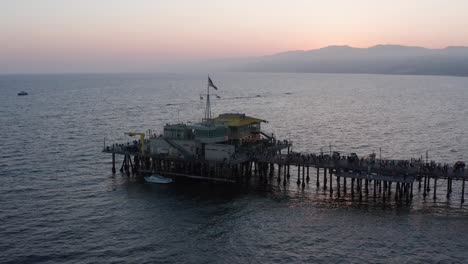 aerial close-up panning shot of the restaurant at the end of the santa monica pier on a busy summer night at twilight
