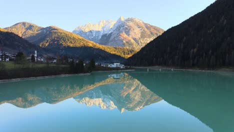 Vista-Aérea-De-Montañas-Cubiertas-De-Nieve-Con-Bosques-Reflejados-En-Un-Lago-De-Agua-Cristalina.