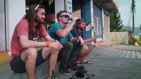 Guys-sitting-on-a-curb-drinking-a-beer-during-their-vacation