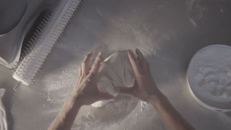 An-overhead-view-of-hands-preparing-bread-dough,-showcasing-the-artisanal-process-of-kneading-and-shaping-the-bread