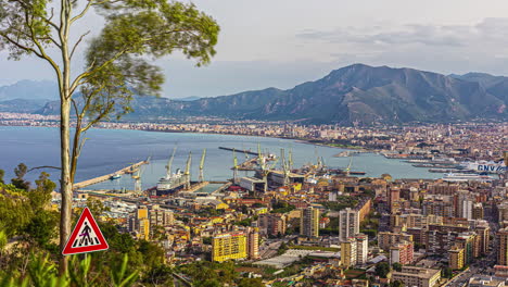 Static-view-of-Foro-Italico-in-Palermo,-Sicily,-Italy-with-view-of-a-harbour-busy-loading-ships-in-the-evening-in-a-timelapse