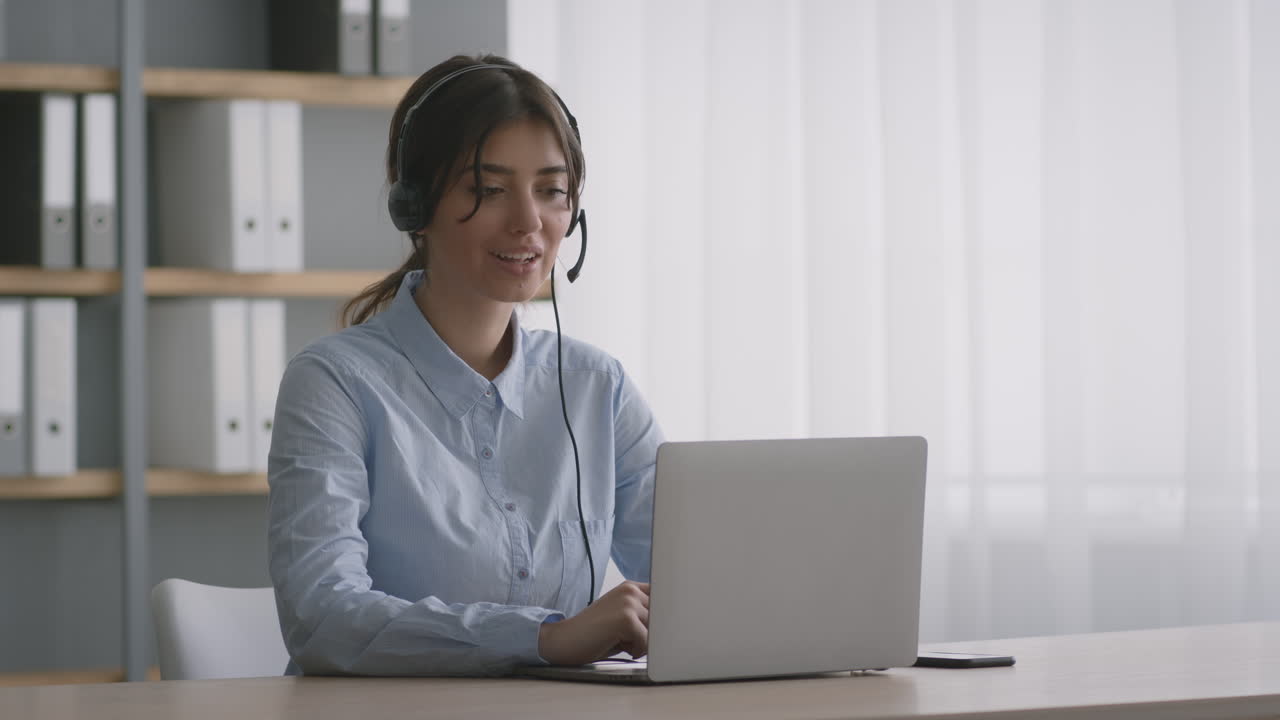 mujer trabajando en una computadora portátil con auriculares en una oficina