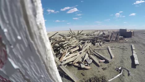 panning past a wooden sign to a pile of old used wood dumped in the middle of nowhere