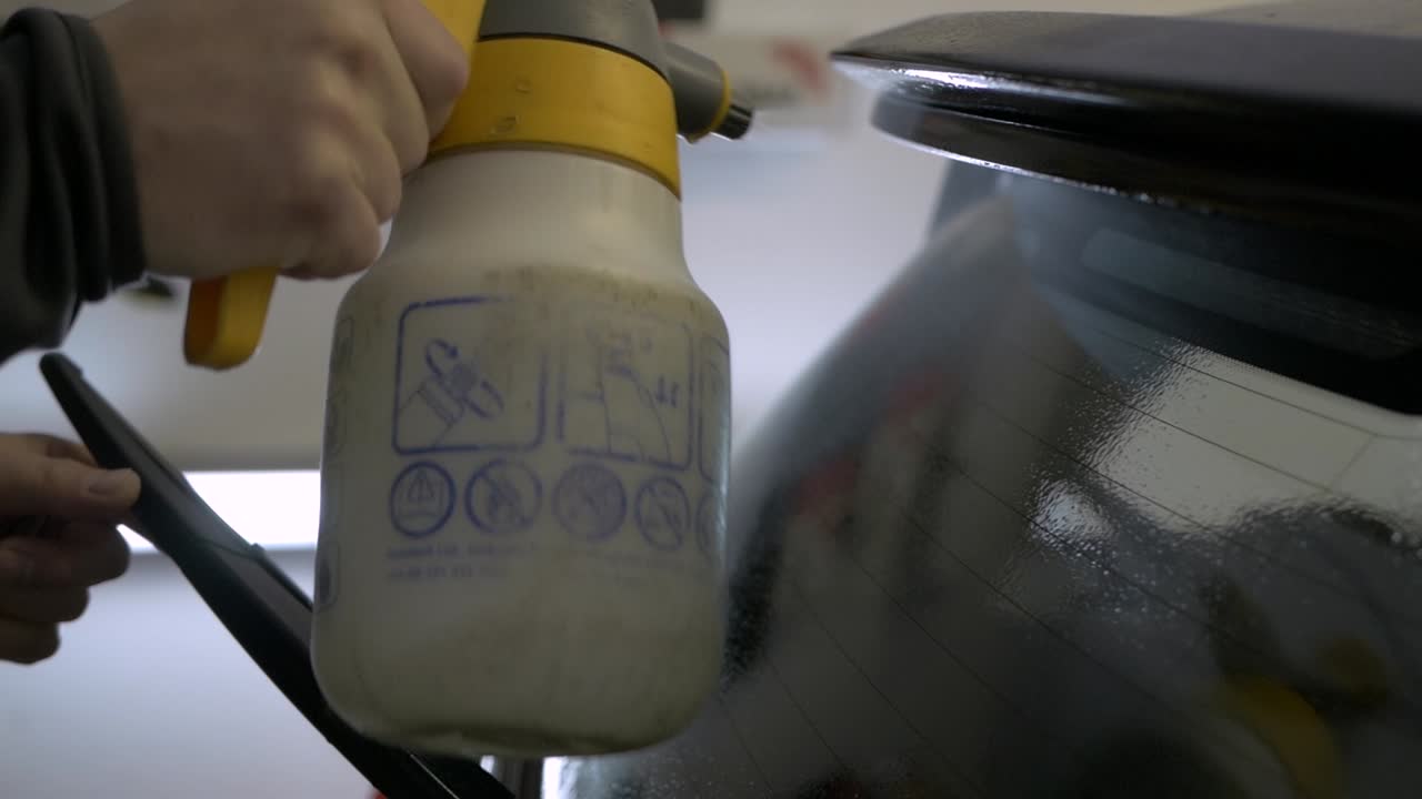 Rear window tint being sprayed for cleaning. Tint foil