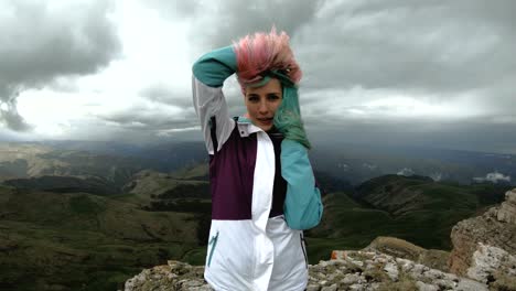 chica mujer joven baila en el borde de un acantilado de una meseta divirtiéndose naturaleza montañas flores hermosas atractivas jugando alegre satisfecho alegría ocio gracioso riendo sonrisa mirando cámara maravilloso paisaje verano feliz fin de semana